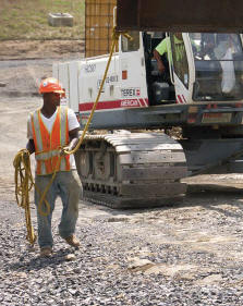 Bridge crew members, including Darrell Vaughn, left, work under the supervision of Superintendent Argel Cook and Foreman Floyd Adkins to move, lift and secure a steel girder that will support a cap form. (Photo by Carl Thiemann)