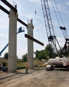 Bridge crew members, including Darrell Vaughn, left, work under the supervision of Superintendent Argel Cook and Foreman Floyd Adkins to move, lift and secure a steel girder that will support a cap form. (Photo by Carl Thiemann)