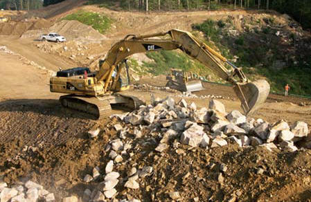 Hoe Operator Phil Hooser repositions rock as Dozer Operator Larry Griffith spreads fill on a lower level in the background on Vecellio & Grogan's East Beckley Bypass project. (Photo by Carl Thiemann)