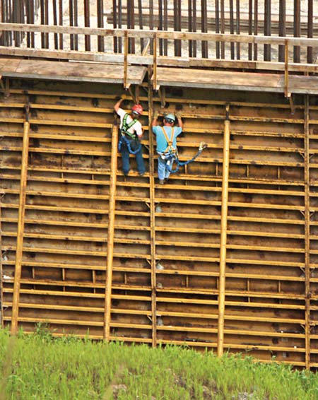 Secure in their harnesses, two bridge crew members work on a pier form on Vecellio & Grogan's East Beckley Bypass project. The piers will rise more than 200 above a deep gorge to support the bridge spans at grade. (Photo by Carl Thiemann)